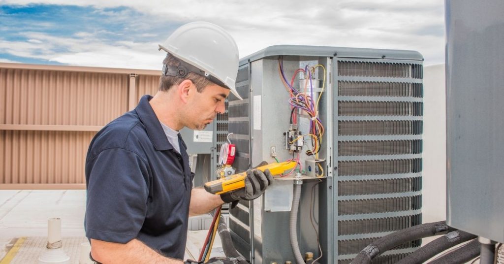A trained HVAC professional performs preventative maintenance on an air conditioning unit.
